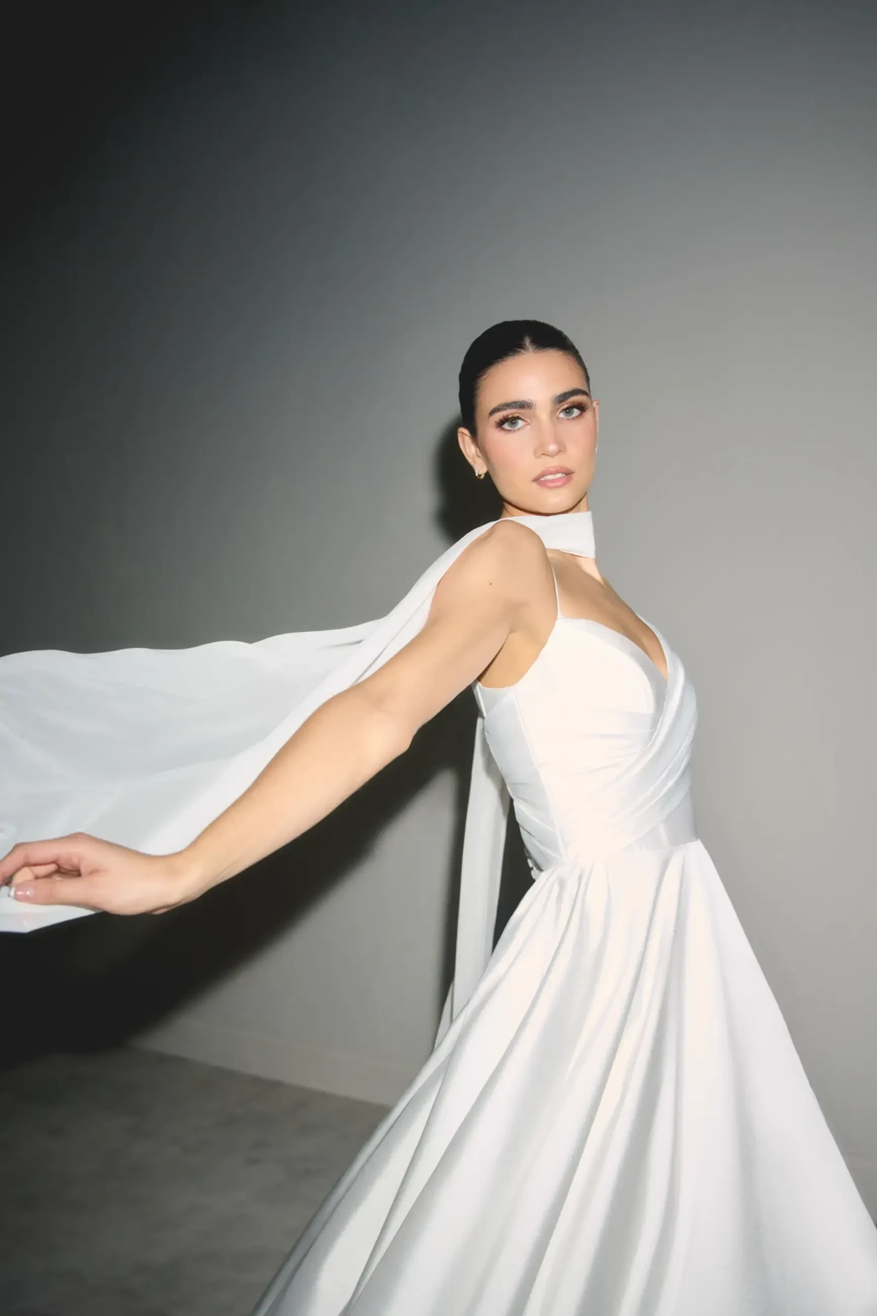 model is wearing a sleeveless bridal gown with a scarf