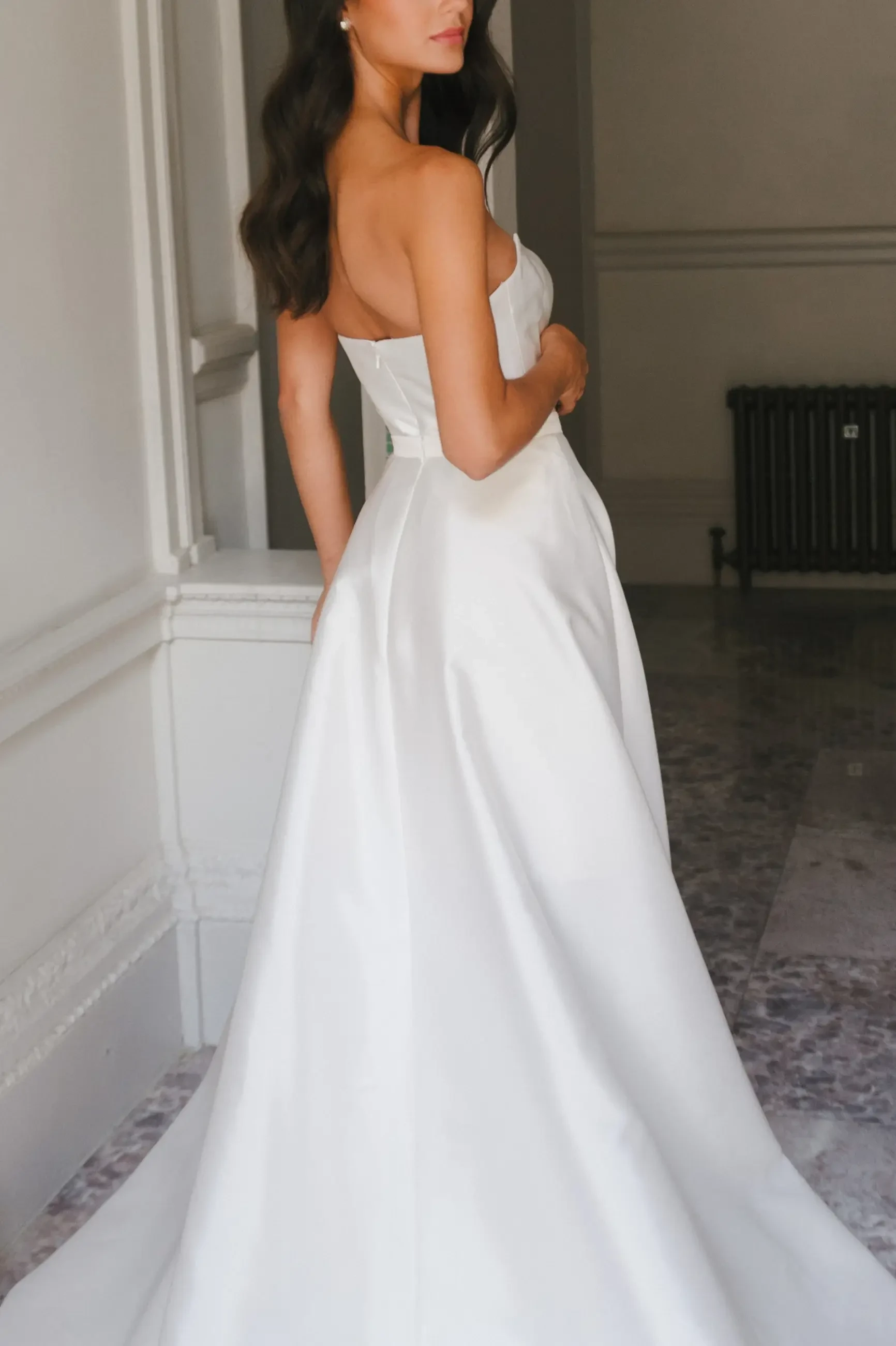 model is wearing a strapless wedding dress by la premiere