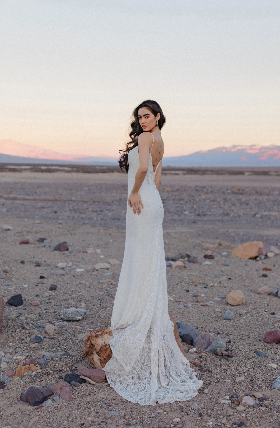 model is wearing a sleeveless open back wedding dress