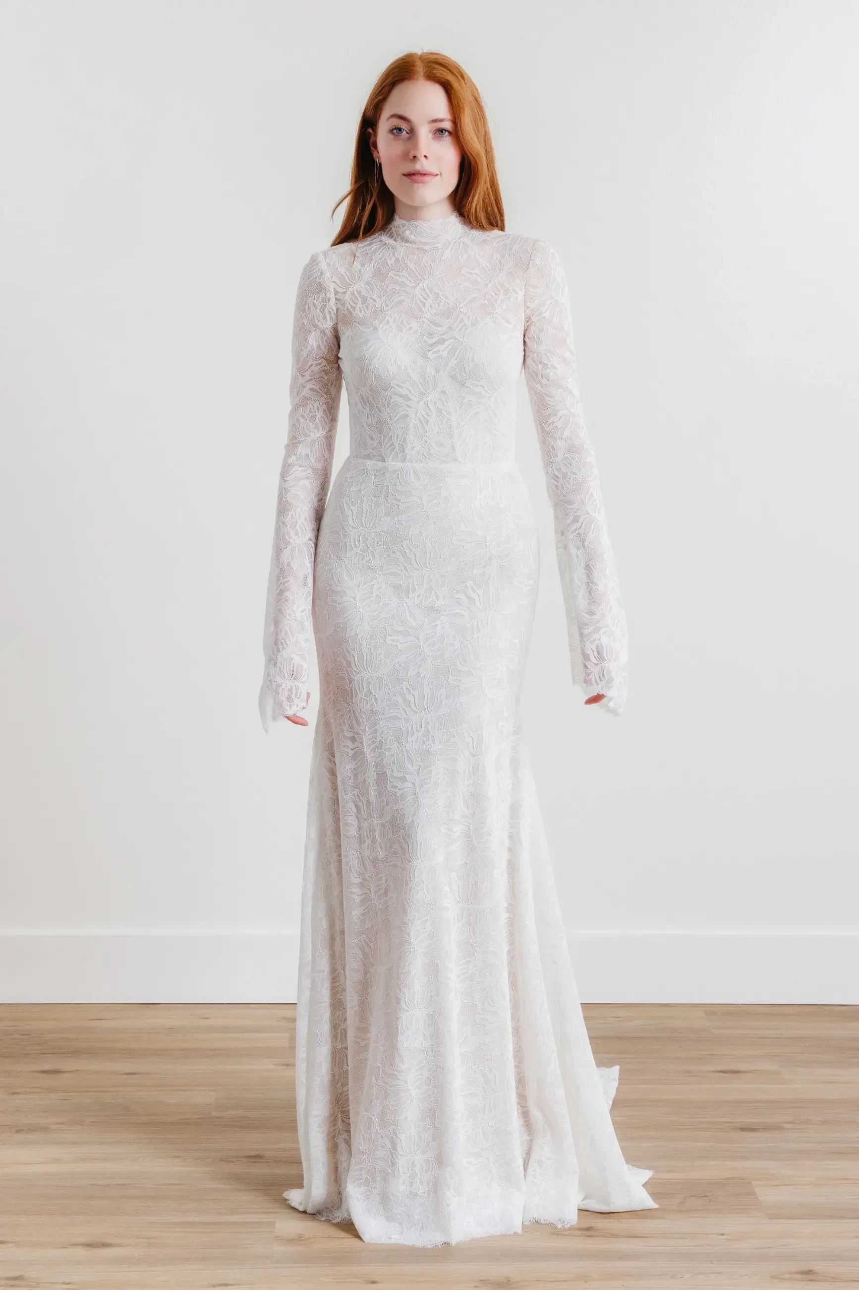 model is wearing a long sleeve high neck allover lace bridal gown