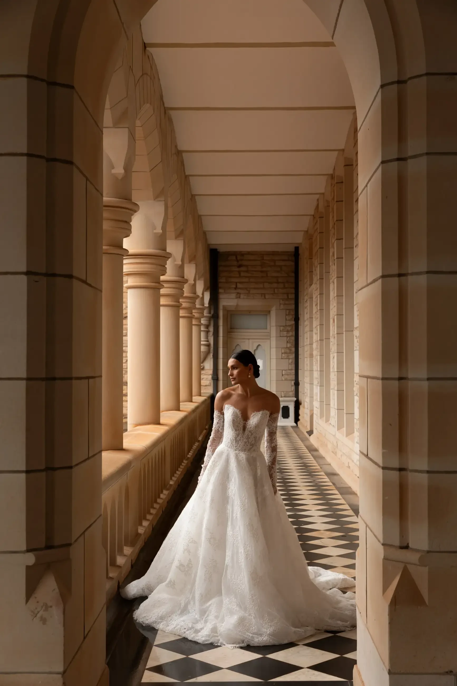 Model is wearing a strapless ball gown wedding dress with detachable long sleeves by la premiere