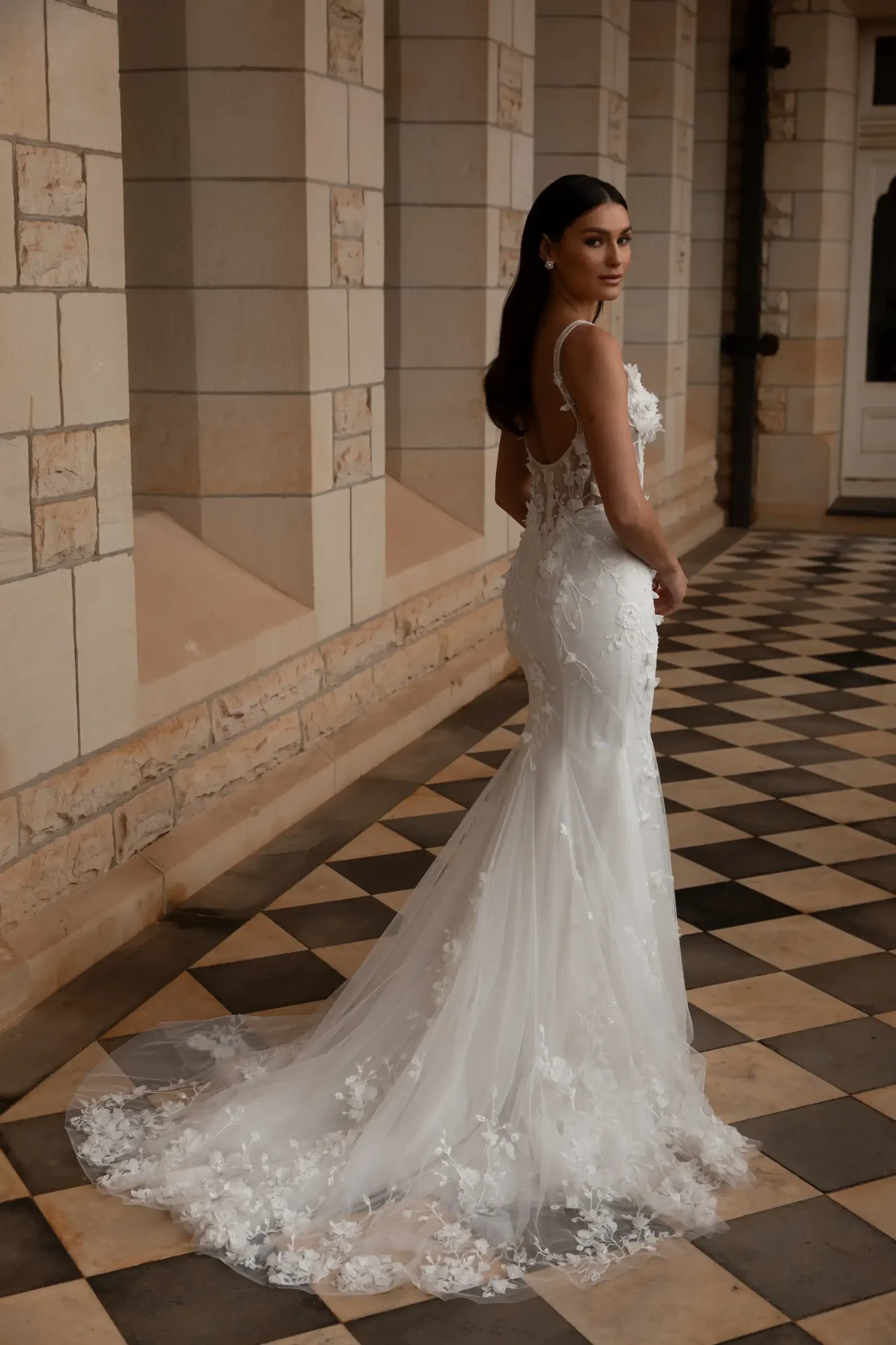model is wearing a sleeveless fit and flare wedding dress with an open back and v-neckline