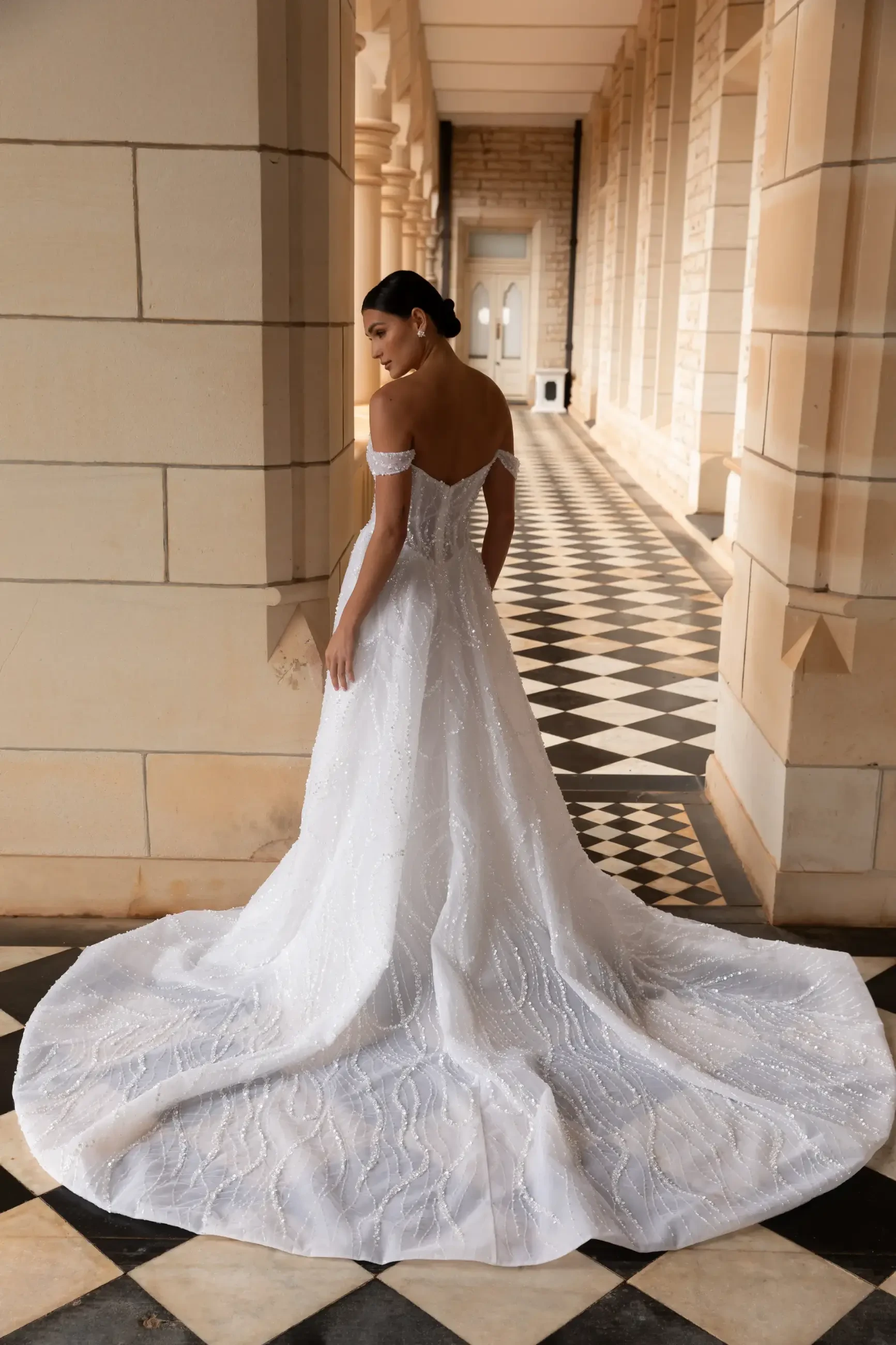 model is wearing an off the shoulder a-line wedding dress from la premiere