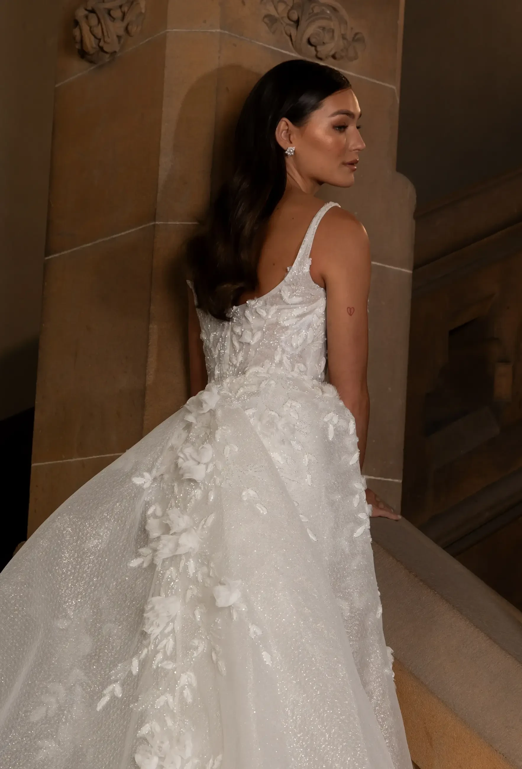 model is wearing a sleeveless wedding dress with a high slit and 3D texture
