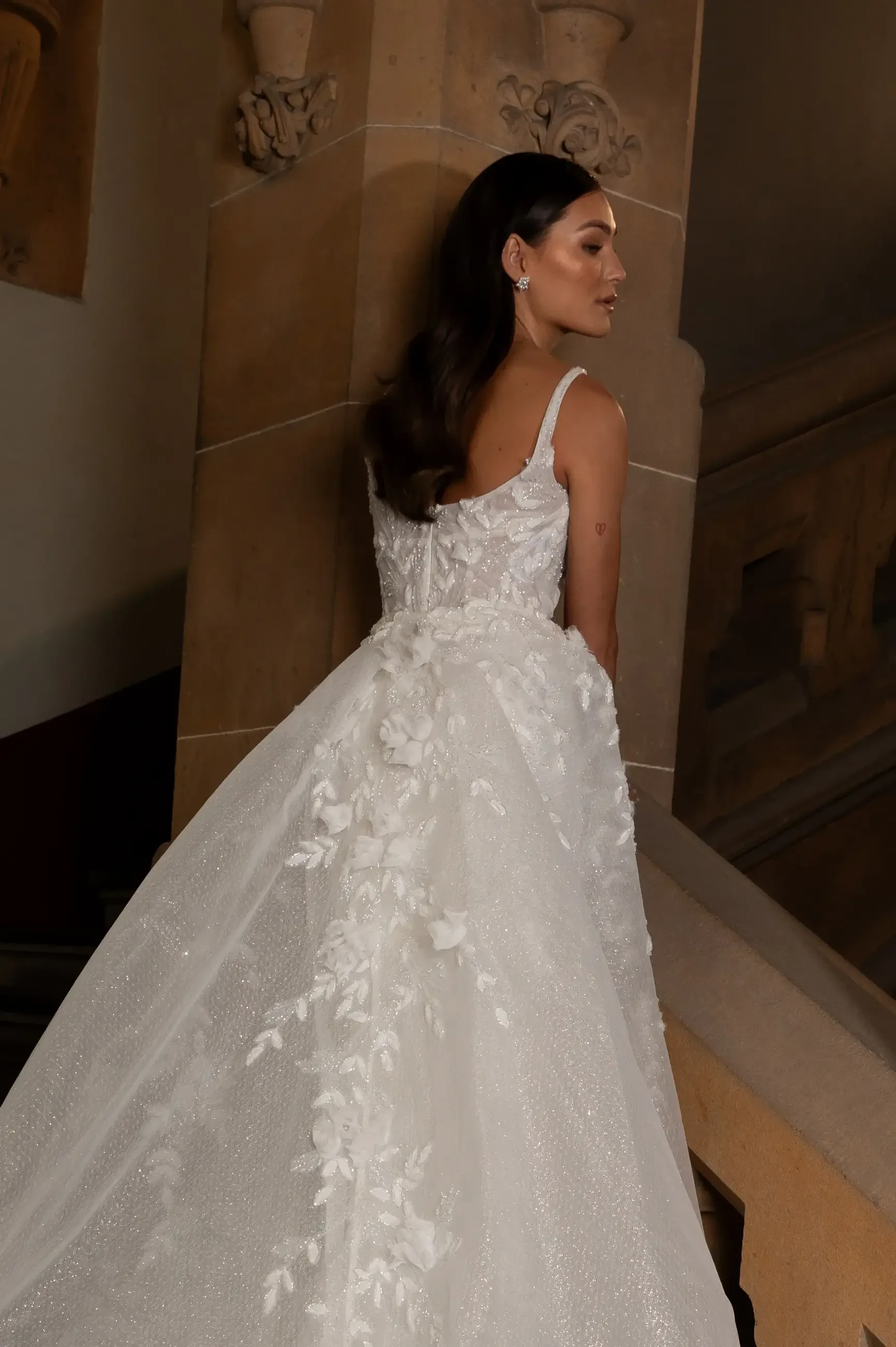 model is wearing a sleeveless sheath wedding dress with plunging neckline and 3D floral appliques with a thigh high slit