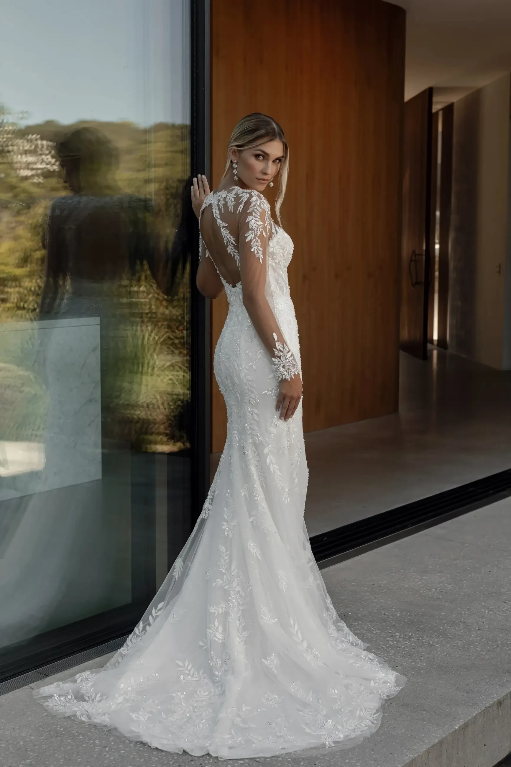 model is wearing an illusion lace long sleeve wedding dress from la premiere