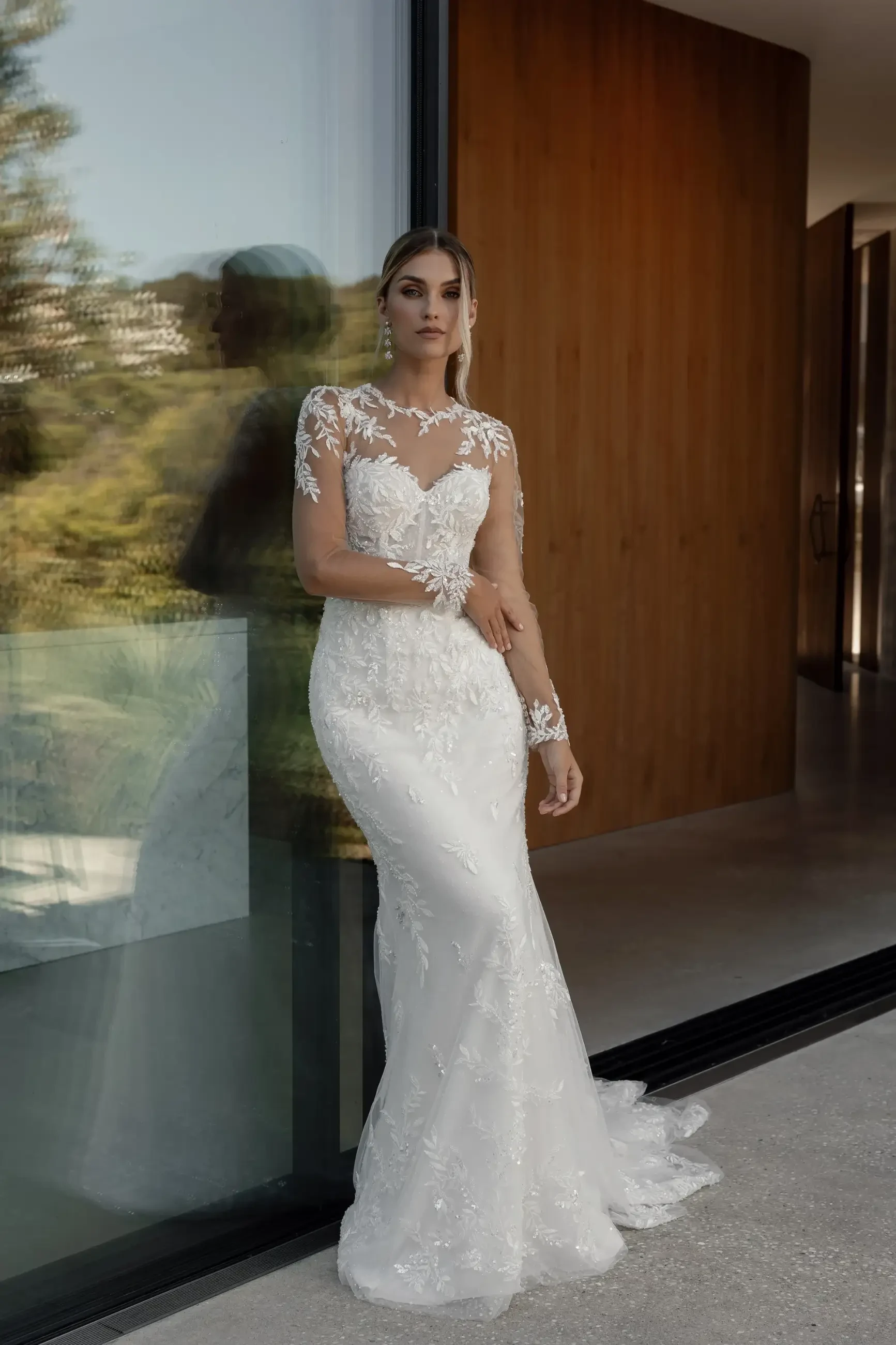 model is wearing an illusion lace long sleeve wedding dress from la premiere