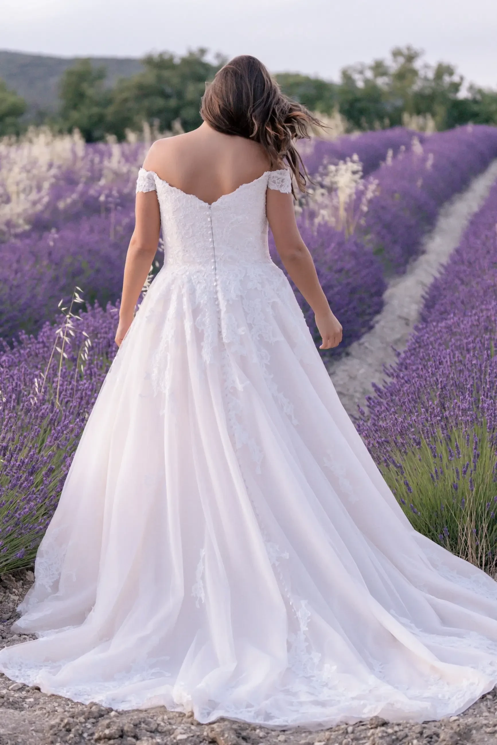 model is wearing a plus size ball gown wedding dress