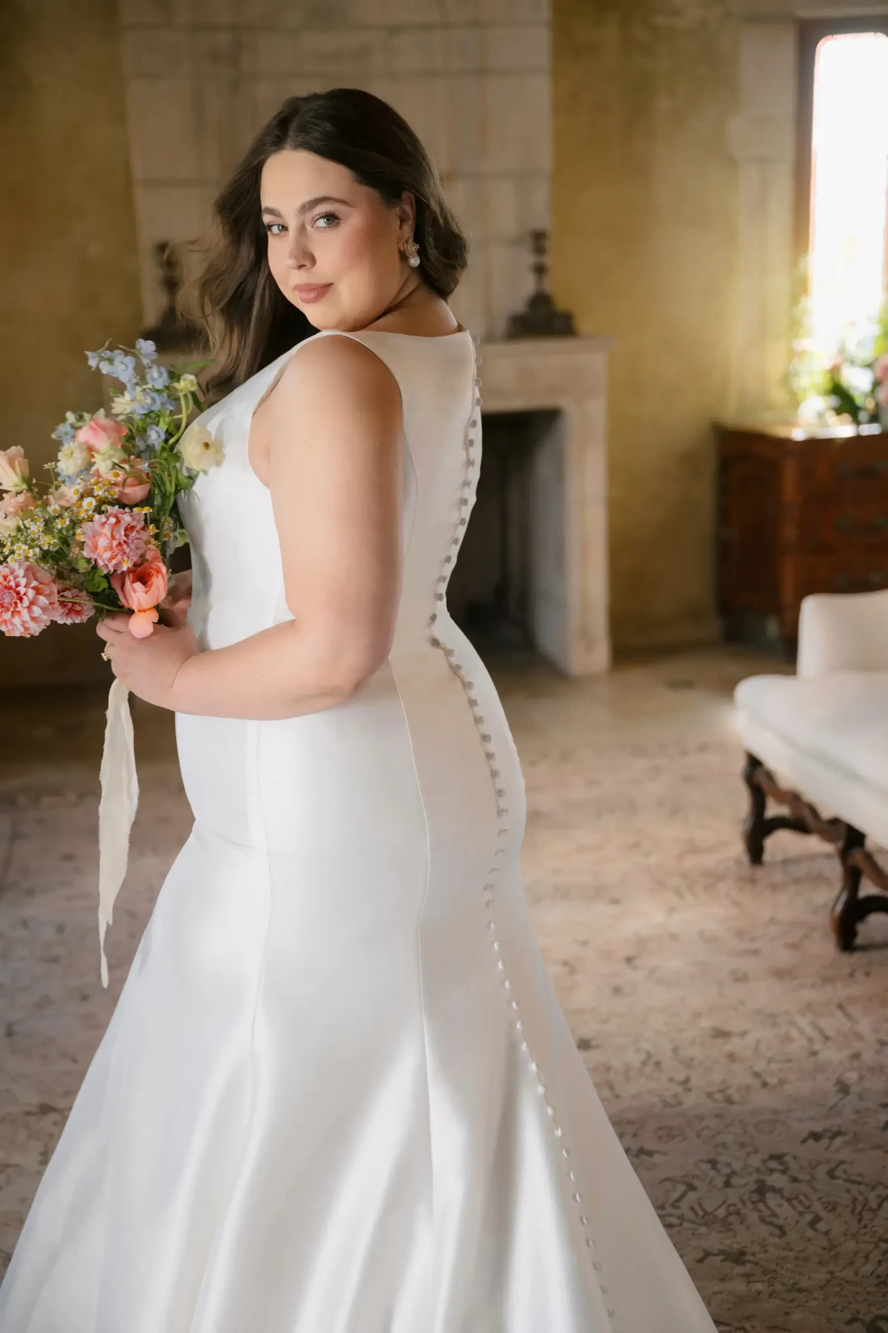 woman is wearing a sleeveless bridal gown